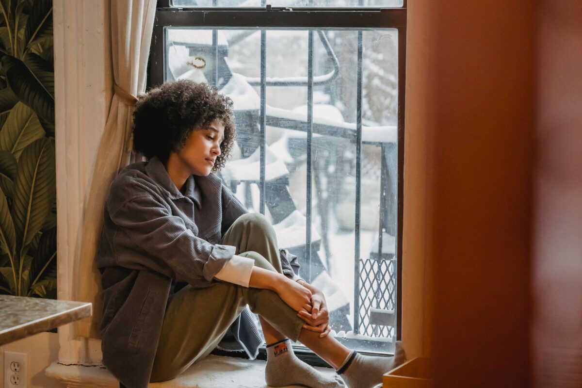 Người mẹ sau sinh mệt mỏi ngồi bên cửa sổ